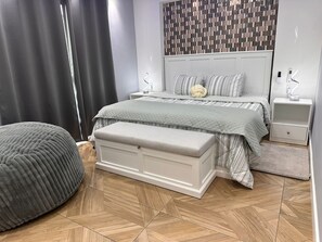 Ein modernes Schlafzimmer mit Bett, Nachttischen, einer Bank und einer Wand mit Muster.