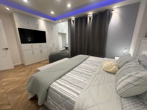 Ein modernes Schlafzimmer mit Bett, Fernseher und Kleiderschrank.