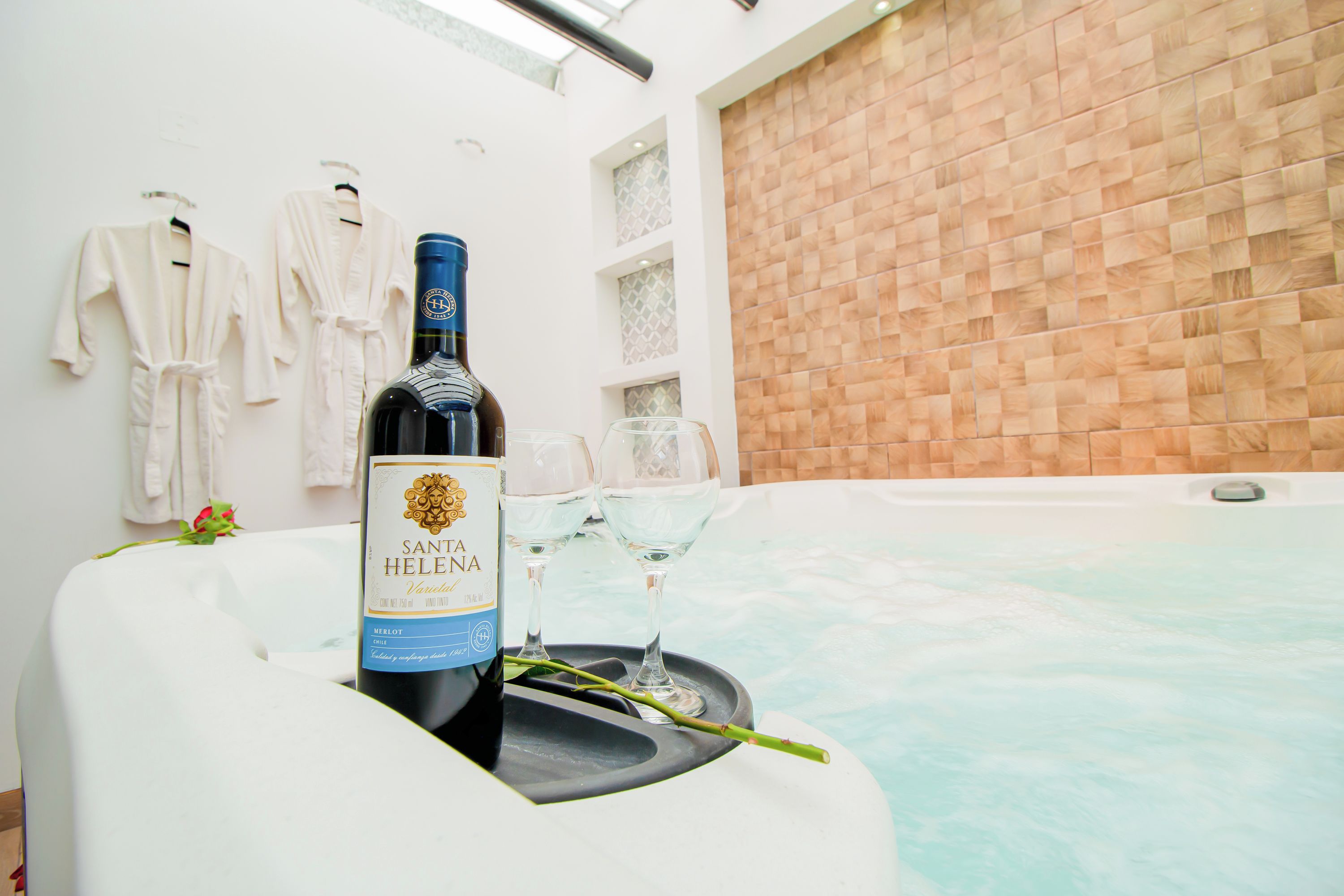 Una botella de vino Santa Elena en una bañera con vasos y una rosa.