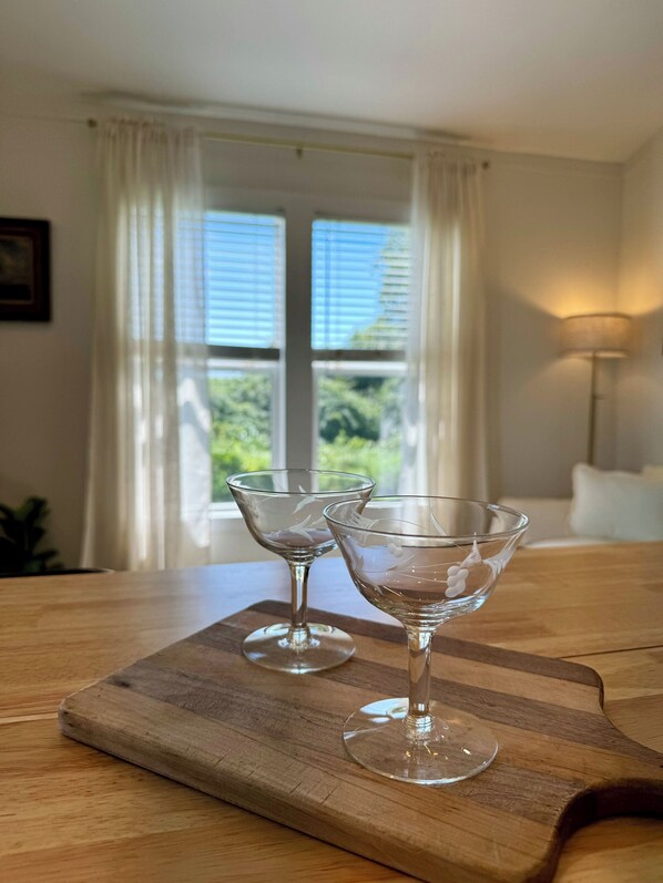 A wooden table with two clear glass goblets on a wooden board. - La Petite Maison - Tiny Home in Victoria, TX (Victoria)