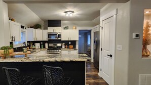 A modern kitchen with a central island, white cabinetry, and a black countertop. - Guest Favorite, Peaceful, Walkable to Dinning & Shopping. 5-Star clean! (Coeur d'Alene)