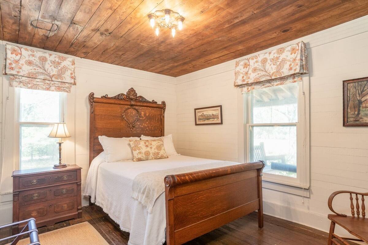 Ein Schlafzimmer mit einem hölzernen Bett, einem Nachttisch, einer Kommode und einem Stuhl.