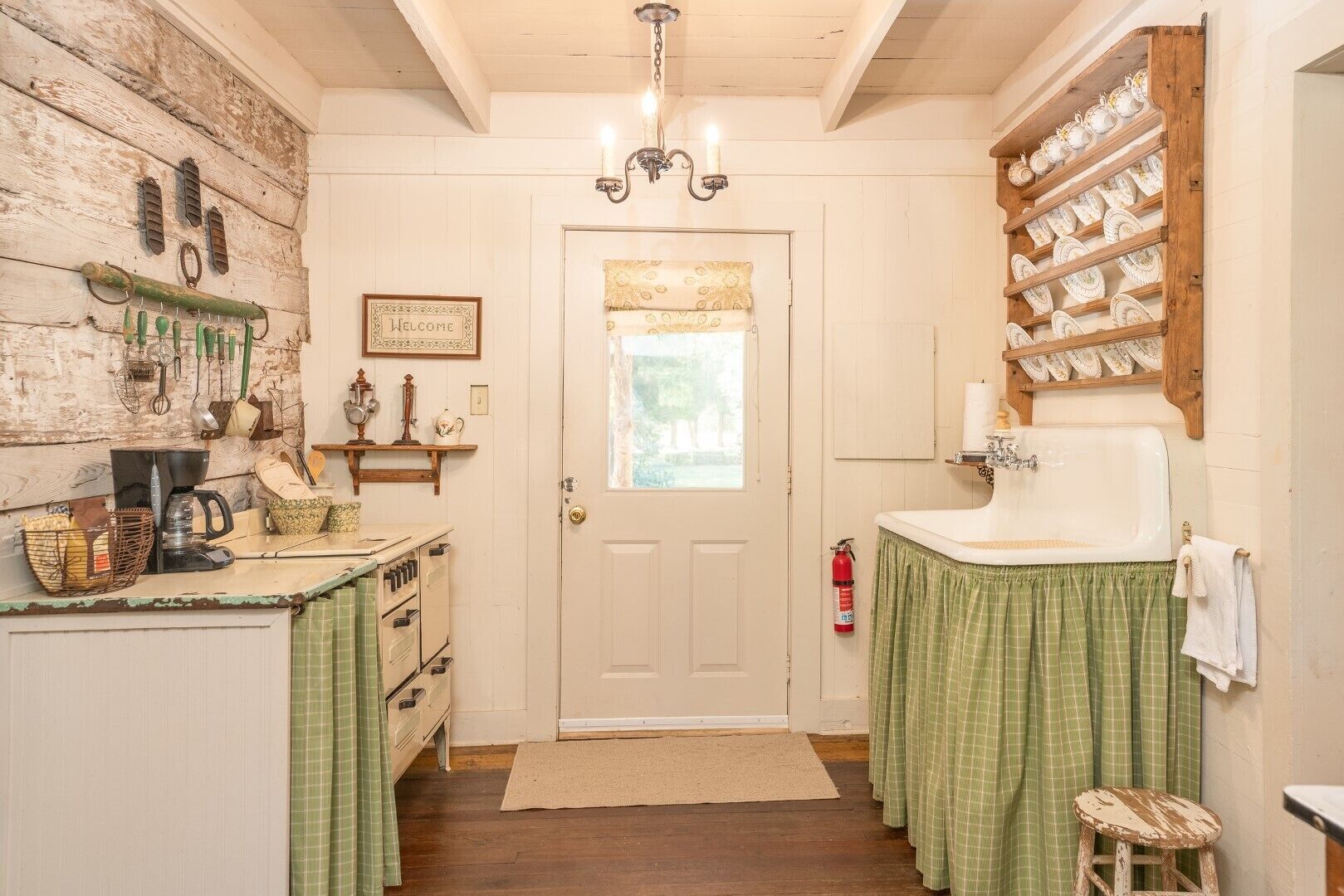 A kitchen with a wooden wall, a coffee maker, and a sink with a green curtain.