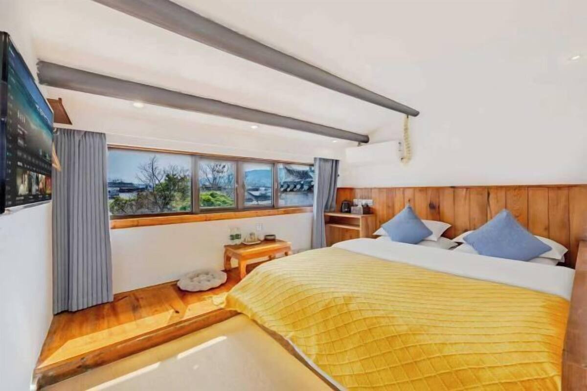 A modern bedroom with a large bed, wooden headboard, and a view of the outdoors.