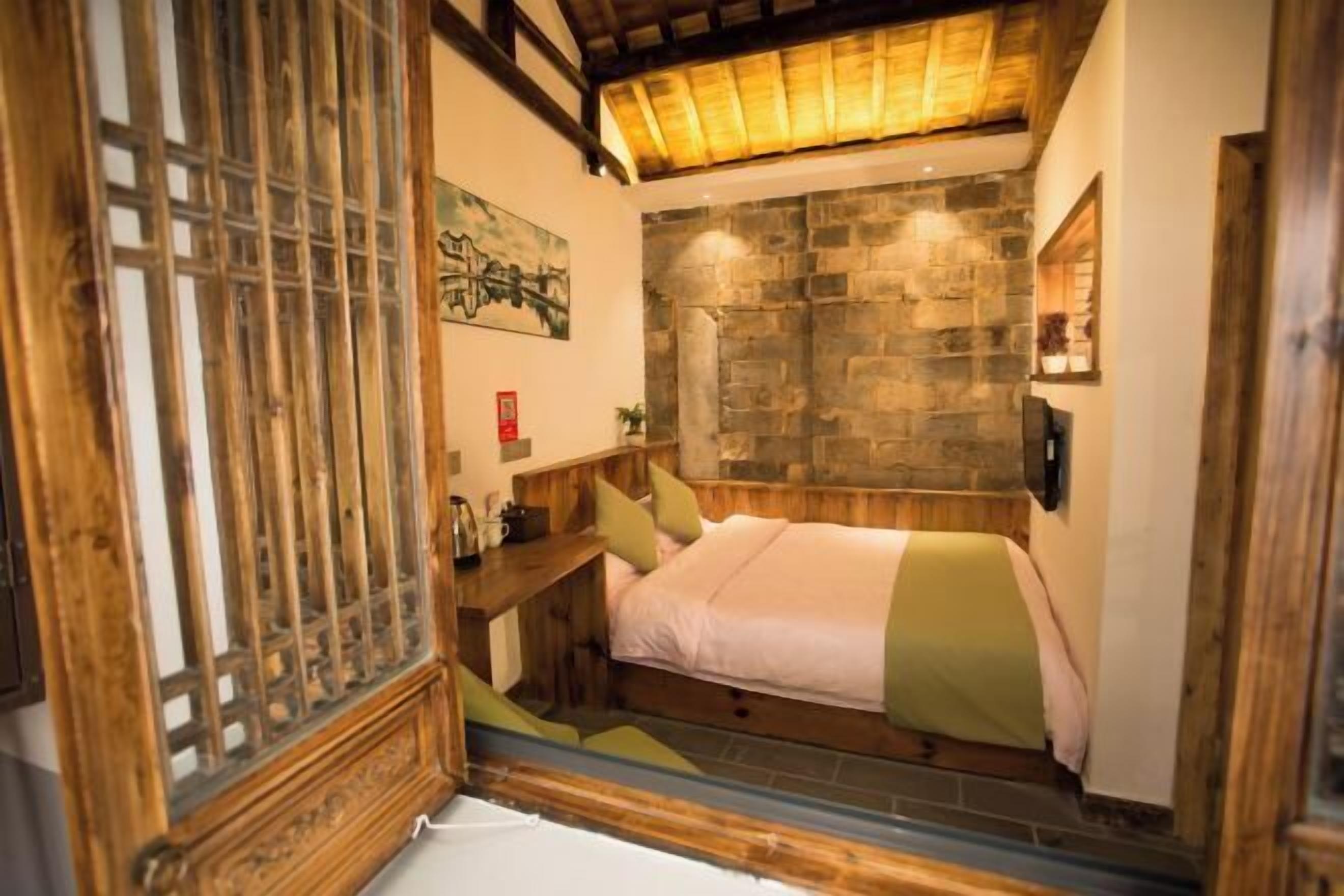 Ein Schlafzimmer mit Steinwand, hölzernem Bettgestell und traditioneller japanischer Shoji-Schirm.