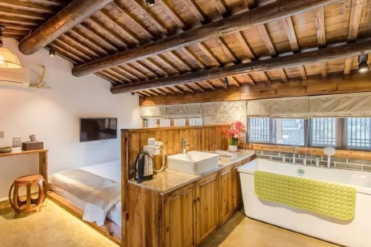 A rustic bathroom with wooden beams, a sink, and a bathtub.