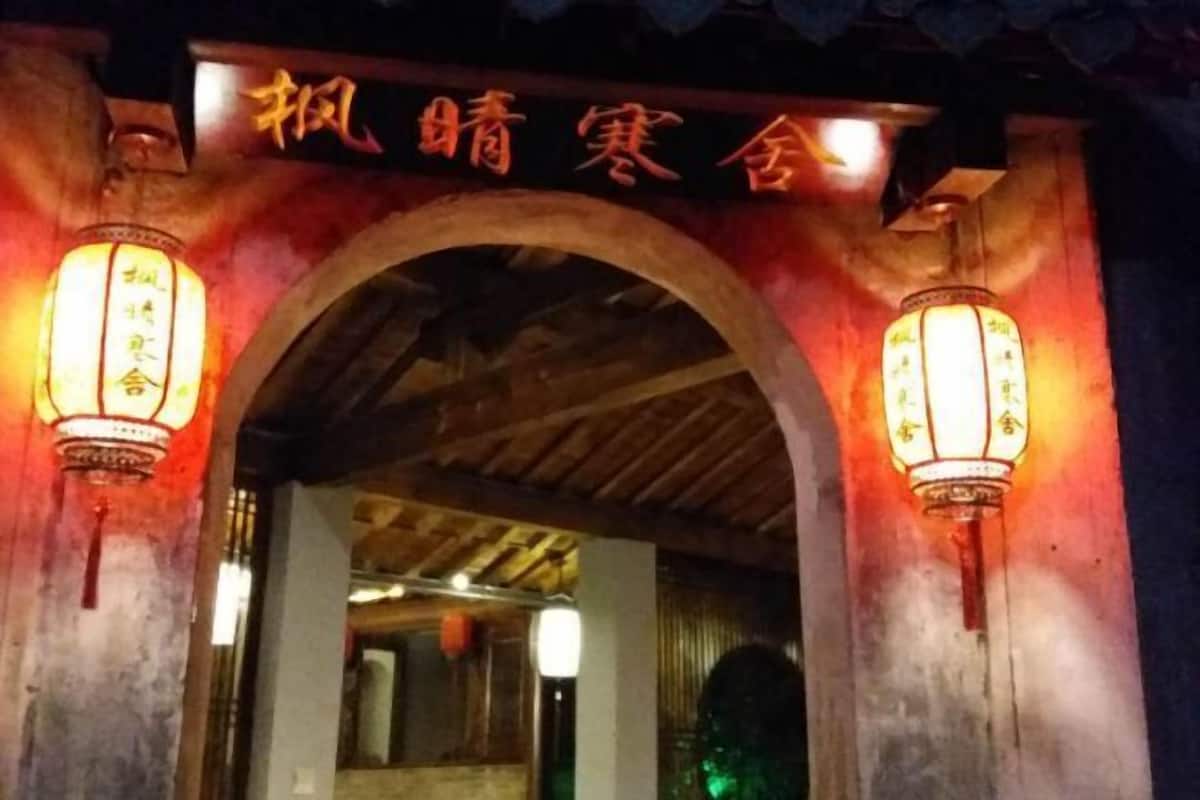 An entrance with a sign and two illuminated lanterns.