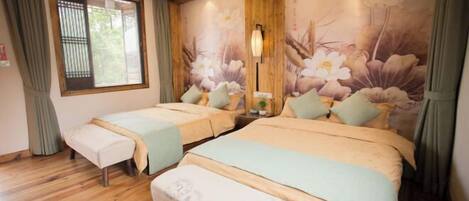 A hotel room with two beds, wooden flooring, a window with curtains, and a floral wall mural.
