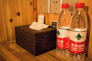 A wooden room with a tissue box, two bottles of water, and a phone on a wooden surface. - Hongcun Fengqing Cold House (Yi County)