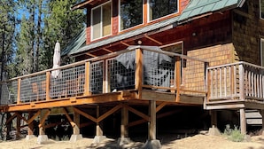 A wooden cabin with a deck, large windows, and a chimney.