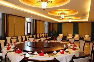 Un salón de conferencias con una mesa redonda rodeada de sillas, una araña y un ventanal grande.