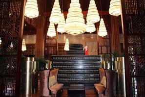 Zona de recepción con una escalera, mostrador de recepción y varias lámparas colgantes.