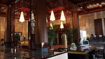 A lobby with a reception desk, seating area, and decorative lighting.