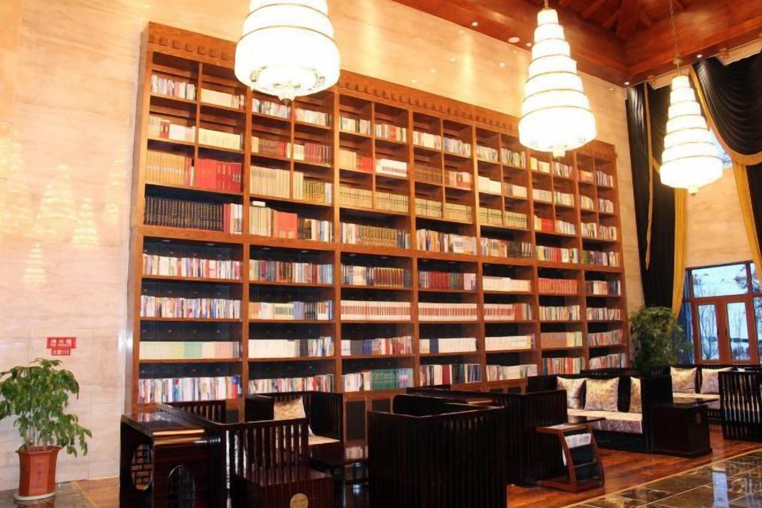 A library with bookshelves, seating, and a chandelier.