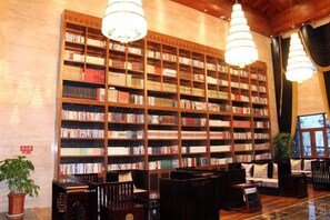 Una biblioteca con estanterías, asientos y una araña.