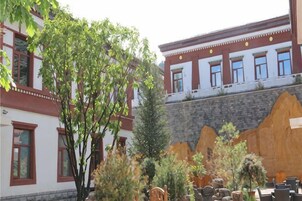 Un patio con un edificio de arquitectura tradicional, un árbol y mobiliario exterior.