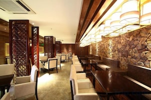 Vestíbulo de hotel con zona de bar, arreglos de asientos y detalles decorativos.
