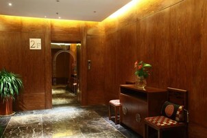 Un vestíbulo con paneles de madera, un mostrador de recepción, una silla y una planta en maceta.