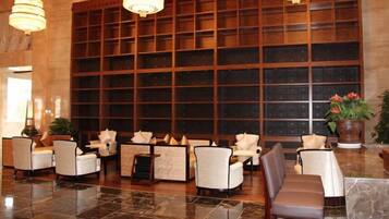 A lobby with multiple seating areas, a large wooden bookshelf, and a marble floor.