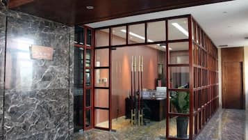A lobby with a marble floor, a reception desk, and a glass partition.