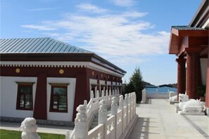 Un edificio con fachada roja y blanca, un corredor cubierto y estatuas blancas.