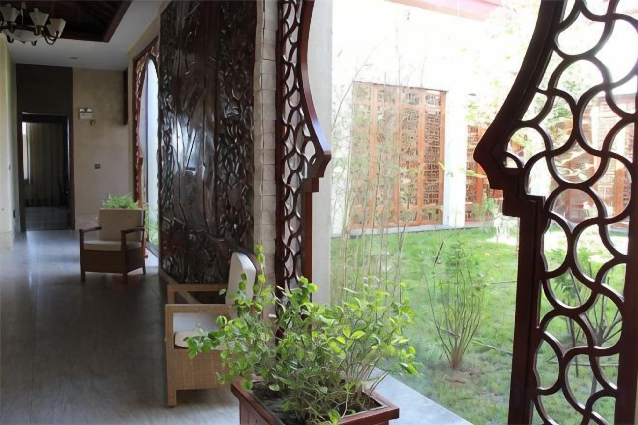 A hallway with a wooden partition, two chairs, and a potted plant.