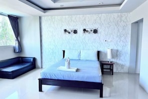 Une chambre d’hôtel moderne dotée d’un grand lit, d’un coin salon, de murs en marbre et d’un plafond avec des spots encastrés.