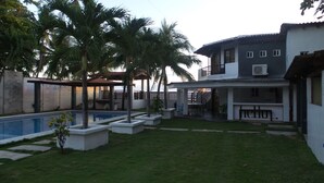 Une propriété résidentielle dotée d’une piscine, d’un patio couvert et d’une maison à deux étages avec un balcon.
