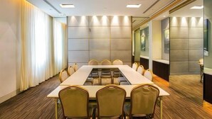 Ein Konferenzraum mit langem Tisch und Stühlen, Holzboden und modernem Design mit eingelassener Beleuchtung.