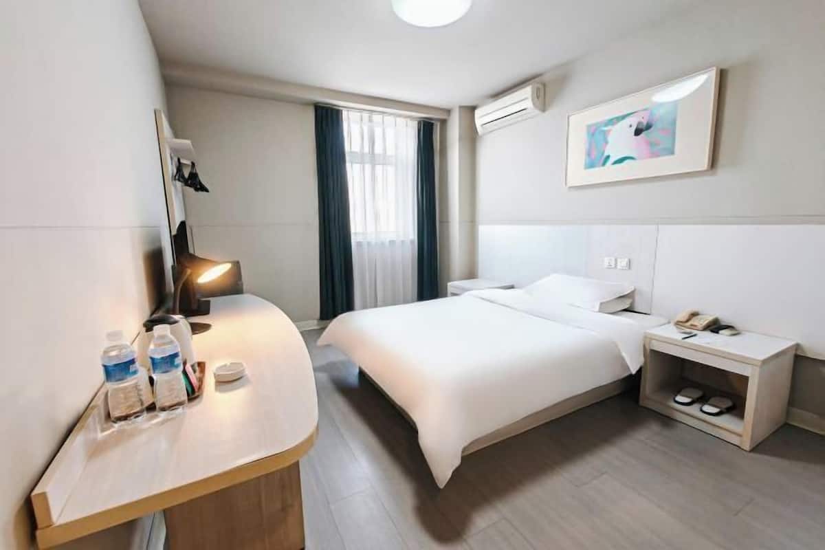 Una habitación de hotel con cama, mesita de noche y mesilla.