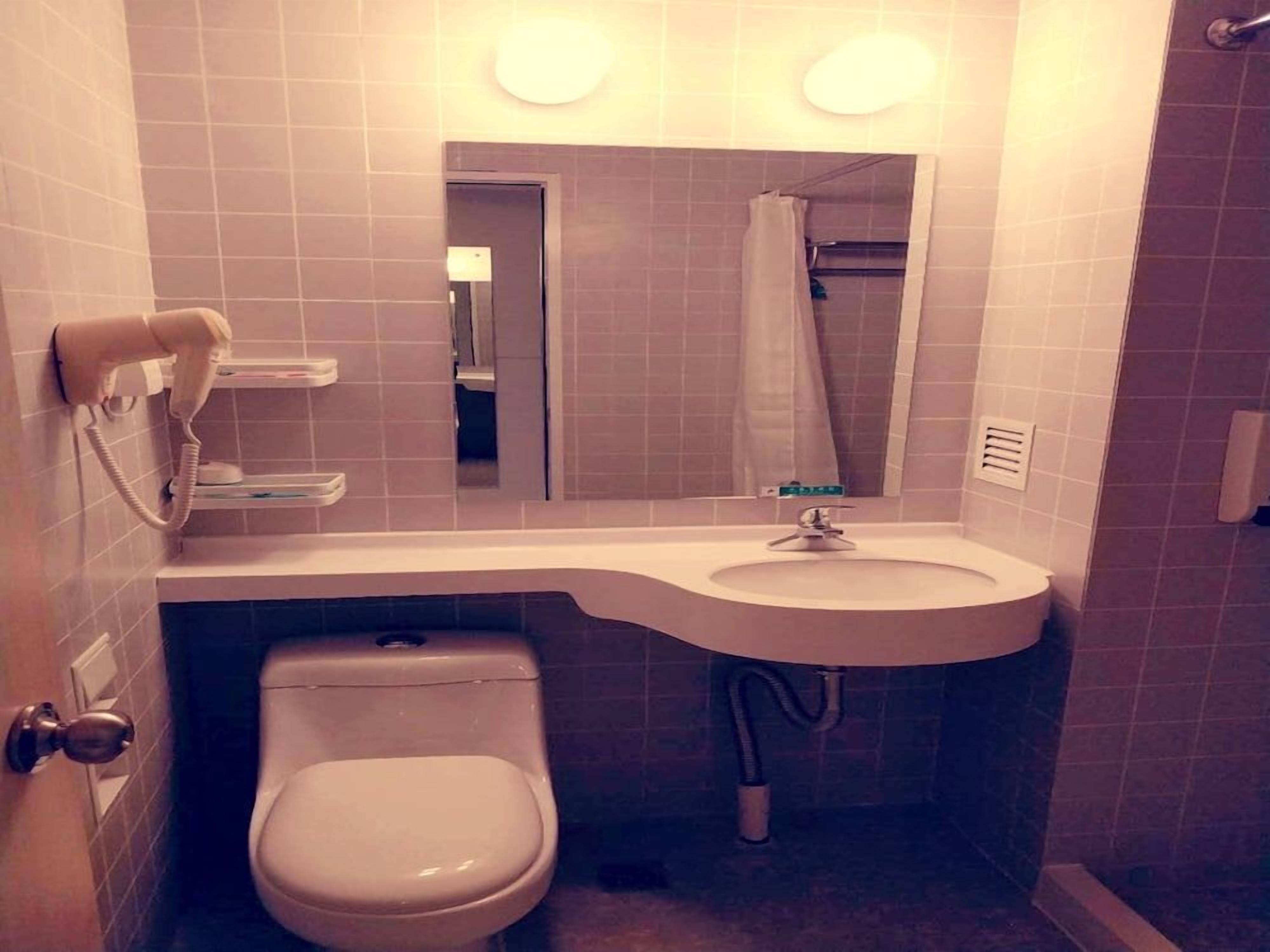 A compact bathroom with a toilet, sink, and a mirror above the sink.
