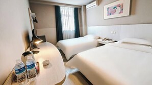 Ein Hotelzimmer mit zwei Betten, einem Schreibtisch mit Lampe, einer Wasserflasche und einem Gemälde an der Wand.