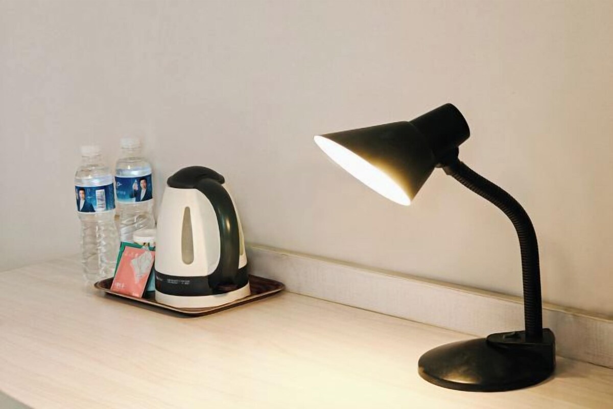 Ein Schreibtisch mit einem Wasserkocher, Wasserflaschen und einer Schreibtischlampe.