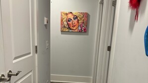 Un pasillo con suelo de madera, paredes blancas y un cuadro en la pared.