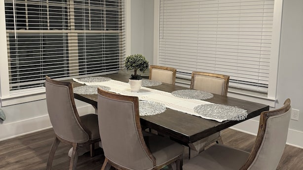 Un comedor con una mesa rectangular, seis sillas, una planta en maceta y un lámpara en el techo.