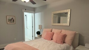Un dormitorio con cama, mesita de noche y ventilador de techo.