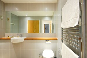 A modern bathroom with a sink, mirror, and towel rack.