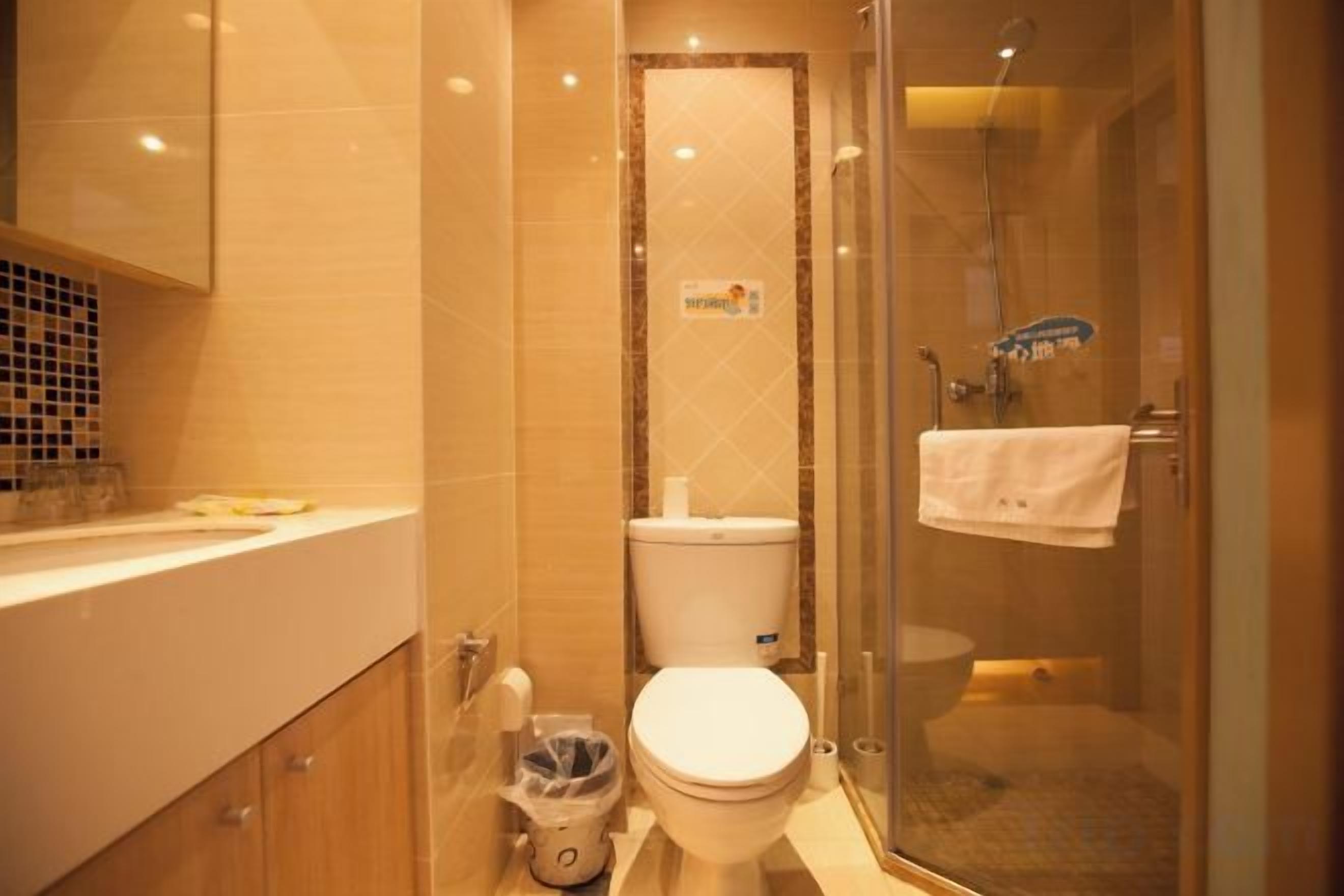 A bathroom with a toilet, a glass shower enclosure, and a sink.