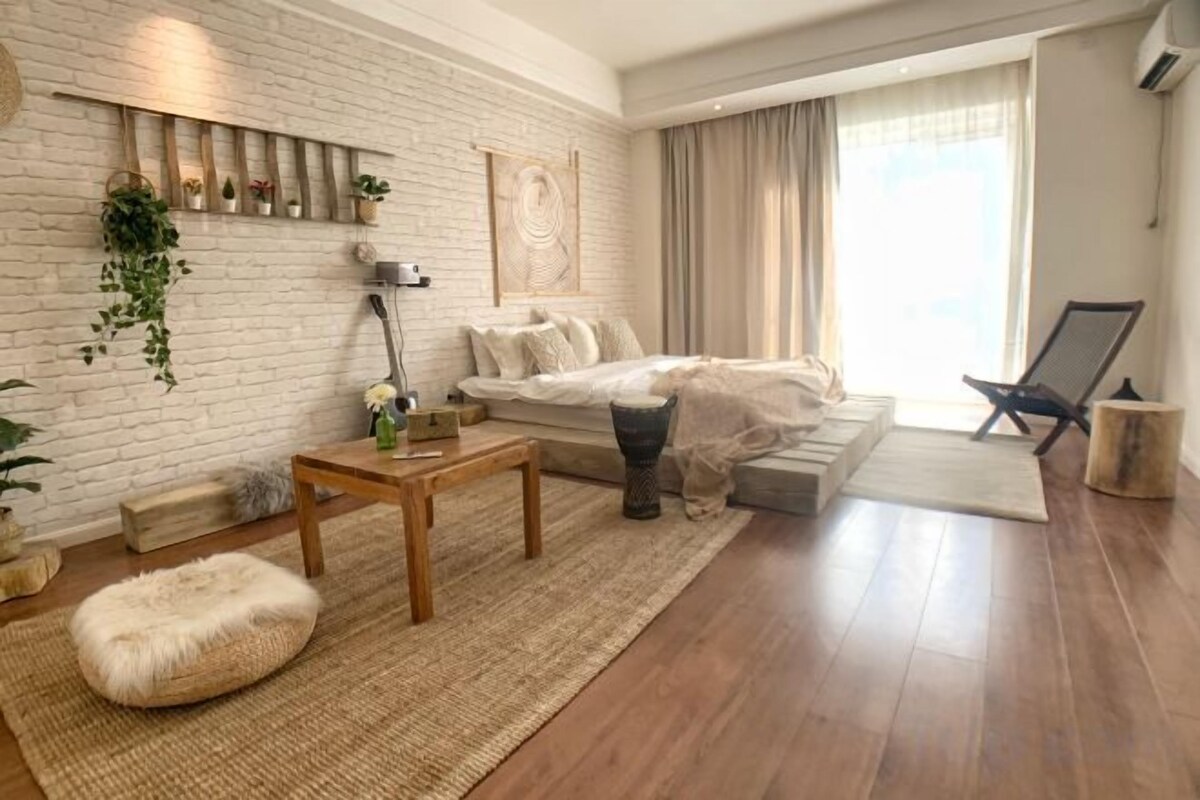 A modern living room with a white brick wall, a sofa, a coffee table, and a large window with curtains.