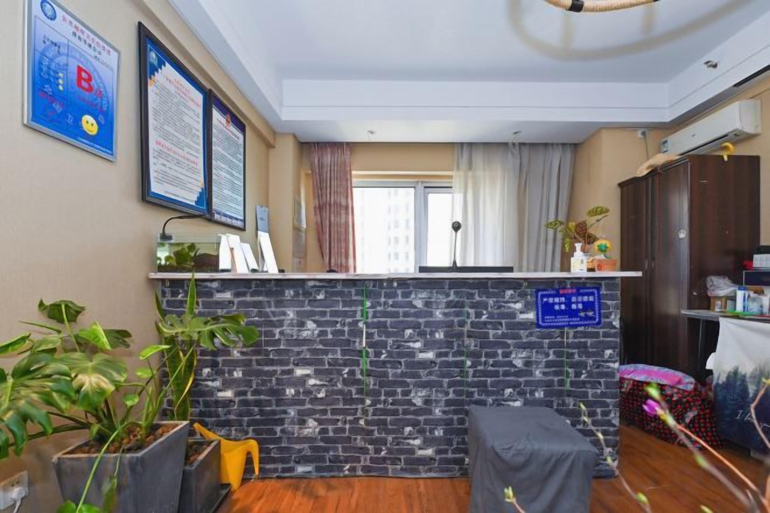 A reception area with a brick wall, a reception desk, a window with curtains, and a plant.