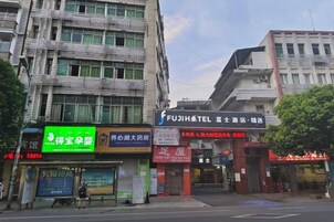 A building with multiple storefronts, including a hotel named 'Fujihotel' and a store with a green sign.