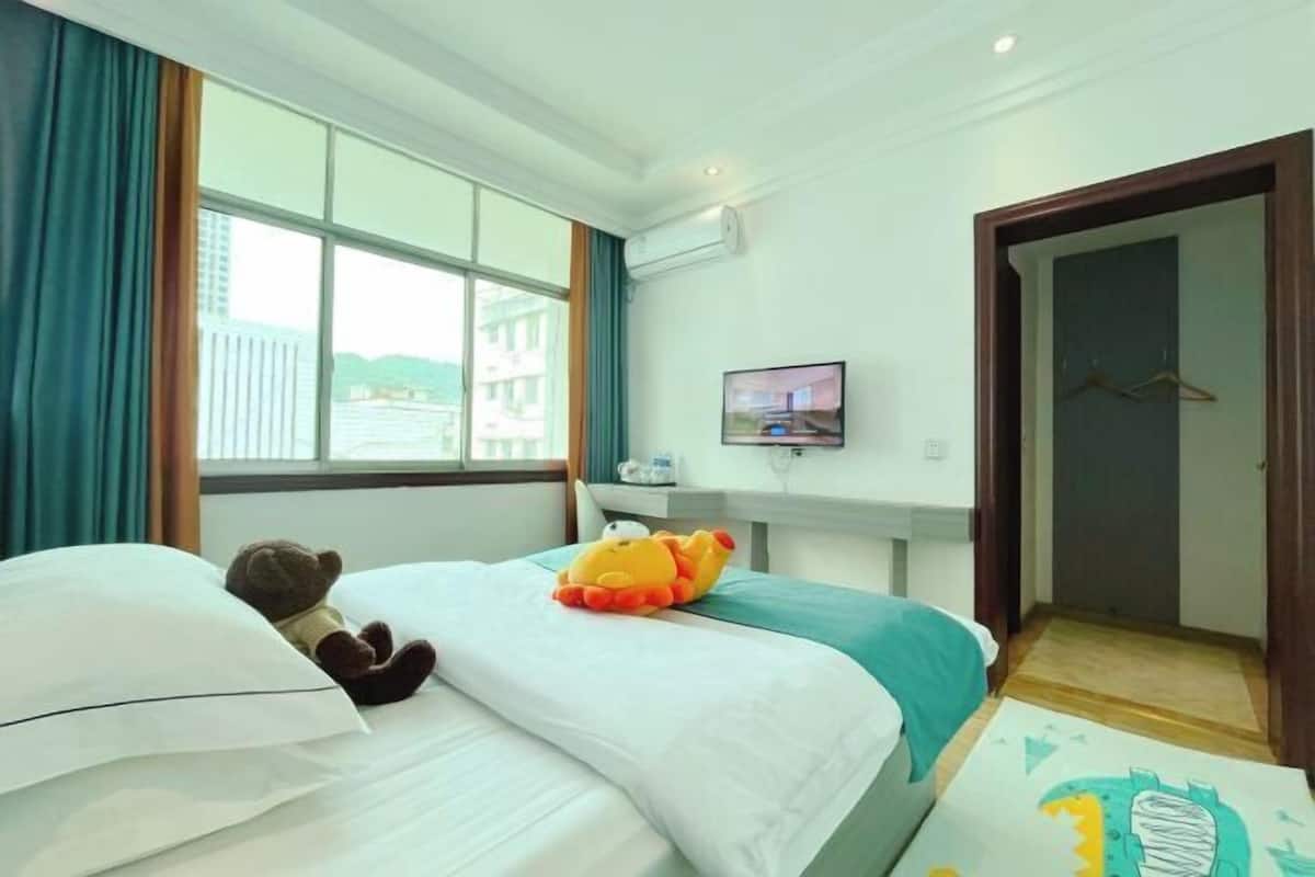 Een hotelkamer met een bed, een televisie, een raam met gordijnen en een deur.