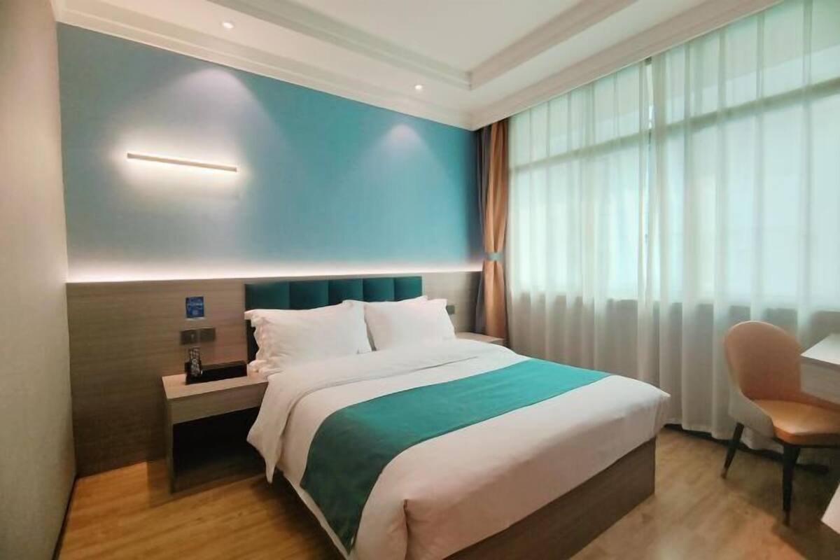 Een hotelkamer met een bed, nachtkastje en een stoel.