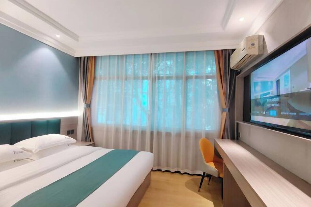 Een hotelkamer met een bed, een bureau, een stoel en een televisiescherm.