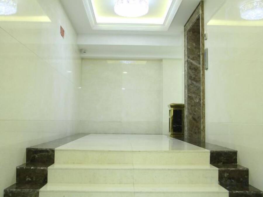 Un conjunto de escaleras de mármol que conducen a una puerta, con un candelabro en el techo.