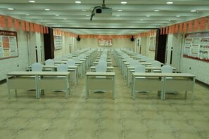 A conference room with rows of tables and chairs, a projector, and informational posters on the walls. - Jiangpan Business Hostel (Harbin)