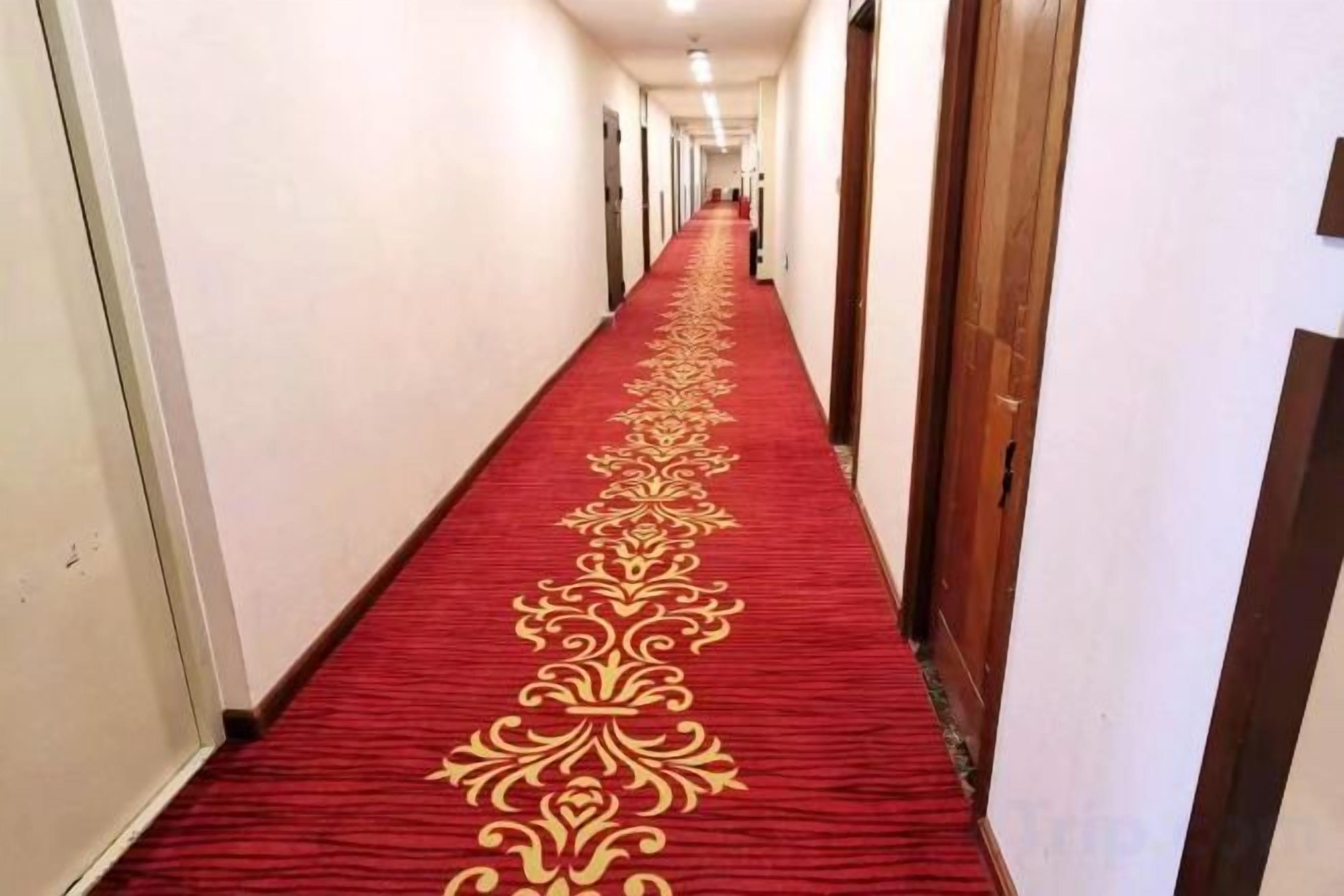 A long hallway with a red carpet and wooden doors.