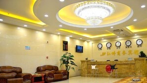 A hotel lobby with leather sofas, a reception desk, a chandelier, and wall clocks. - Jiangpan Business Hostel (Harbin)