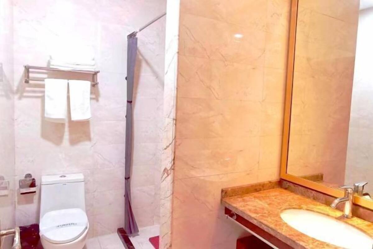 Une salle de bain comprenant des toilettes, un lavabo, un miroir et un espace douche.