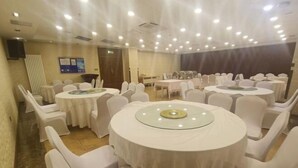 A conference room with round tables and white chairs, equipped with ceiling lights and a projector screen. - Jiangpan Business Hostel (Harbin)